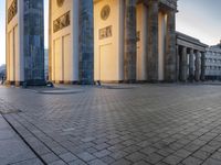 a person sits on top of a stone floor next to a street with pillars in the background