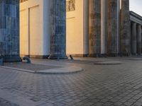 a person sits on top of a stone floor next to a street with pillars in the background