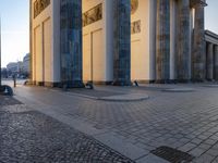 a person sits on top of a stone floor next to a street with pillars in the background