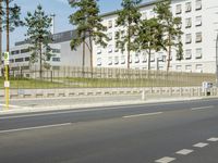 a car driving on the road near tall buildings next to trees and road signs on each side of the road