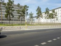 a car driving on the road near tall buildings next to trees and road signs on each side of the road