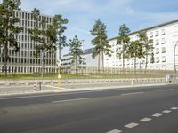 a car driving on the road near tall buildings next to trees and road signs on each side of the road