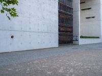 an empty sidewalk with a brick wall in the background and a clock on the building wall