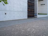 an empty sidewalk with a brick wall in the background and a clock on the building wall