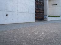 an empty sidewalk with a brick wall in the background and a clock on the building wall