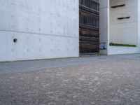 an empty sidewalk with a brick wall in the background and a clock on the building wall