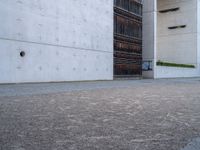 an empty sidewalk with a brick wall in the background and a clock on the building wall