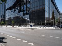 a street that has been empty and empty in the sunshine out front of it is an interesting building with a glass facade