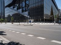 a street that has been empty and empty in the sunshine out front of it is an interesting building with a glass facade