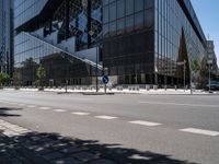 a street that has been empty and empty in the sunshine out front of it is an interesting building with a glass facade