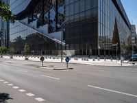 a street that has been empty and empty in the sunshine out front of it is an interesting building with a glass facade