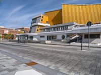 a box sitting in the middle of an empty concrete slab outside a building with a yellow facade