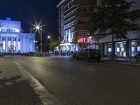 people are standing in line at night at the entrance to an arena with several bikes, and a bike rack on either side