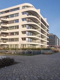 a brick walkway in front of tall buildings in the city with a bench in the foreground