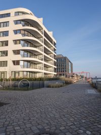a brick walkway in front of tall buildings in the city with a bench in the foreground