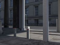 some columns in front of a building on the street and one with a skate board