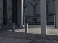 some columns in front of a building on the street and one with a skate board