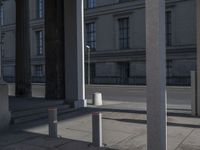 some columns in front of a building on the street and one with a skate board