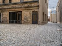 an old brick building with stairs and bicycle racks on one side of the street, outside