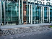 a person walks by a large metal pole near an open brick and glass building with glass walls