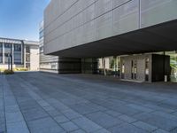 a walkway with multiple stone blocks in front of a building on a clear day, the floor is gray in color