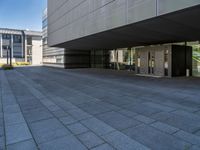 a walkway with multiple stone blocks in front of a building on a clear day, the floor is gray in color