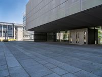 a walkway with multiple stone blocks in front of a building on a clear day, the floor is gray in color