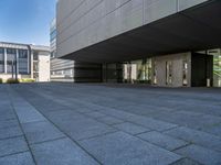 a walkway with multiple stone blocks in front of a building on a clear day, the floor is gray in color