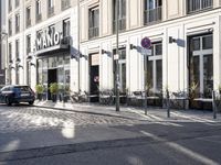 an empty cobbled area in front of a tall building with multiple windows and tables