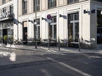 an empty cobbled area in front of a tall building with multiple windows and tables