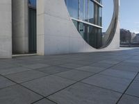 a gray wall that has been designed to have windows inside it and the building in the background is made from white marble tiles