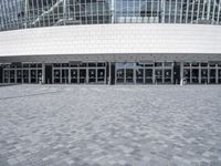 an empty street in front of a large building that has many glass doors and large glass windows