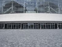 an empty street in front of a large building that has many glass doors and large glass windows