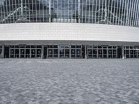 an empty street in front of a large building that has many glass doors and large glass windows