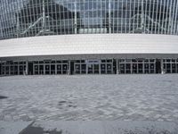 an empty street in front of a large building that has many glass doors and large glass windows