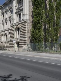 an old building sits on the side of a street with trees surrounding it and a road next to it