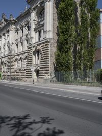 an old building sits on the side of a street with trees surrounding it and a road next to it