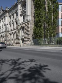 an old building sits on the side of a street with trees surrounding it and a road next to it