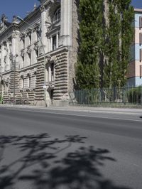 an old building sits on the side of a street with trees surrounding it and a road next to it