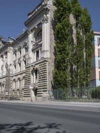 an old building sits on the side of a street with trees surrounding it and a road next to it