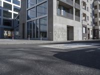 a empty street surrounded by large glass windows in a very big building with a sign on the side of it