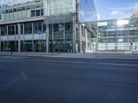 this photo is taken from across the street showing glass building with blue traffic sign in the foreground