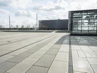 a building made out of glass and a courtyard outside with a brick walkway and a stone tile patio