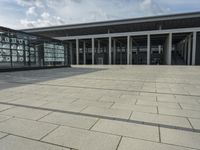 a building made out of glass and a courtyard outside with a brick walkway and a stone tile patio