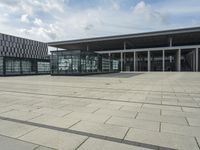 a building made out of glass and a courtyard outside with a brick walkway and a stone tile patio