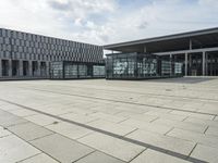 a building made out of glass and a courtyard outside with a brick walkway and a stone tile patio