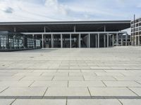 a building made out of glass and a courtyard outside with a brick walkway and a stone tile patio