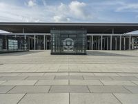 a building made out of glass and a courtyard outside with a brick walkway and a stone tile patio