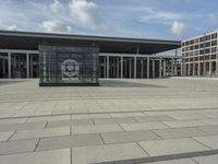 a building made out of glass and a courtyard outside with a brick walkway and a stone tile patio
