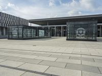 a building made out of glass and a courtyard outside with a brick walkway and a stone tile patio